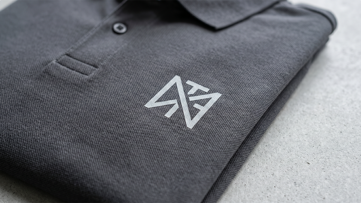 Primo piano di una polo personalizzata piegata con logo minimal che evidenzia la qualità premium ShirtUp!.