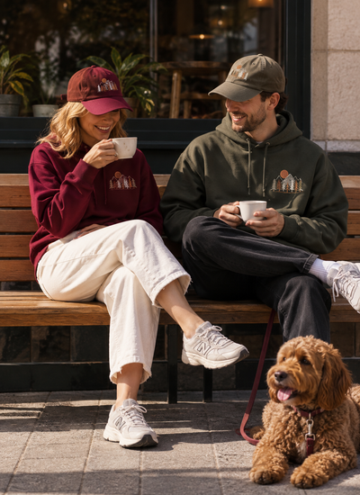 Frau und Mann tragen mit ShirtUp! personalisierte Hoodies und Caps und genießen gemeinsam einen Kaffee.