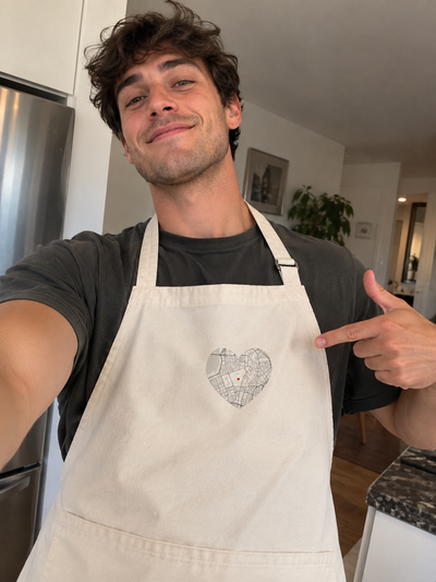Hombre posa señalando el diseño de su delantal personalizado con ShirtUp!.
