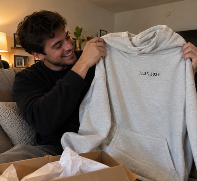 Homme découvrant un sweat à capuche personnalisé avec une date, créé avec ShirtUp! en cadeau.