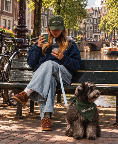 Vrouw met gepersonaliseerde pet en hond met bijpassende gepersonaliseerde bandana, gemaakt met ShirtUp!, aan de Amsterdamse grachten.